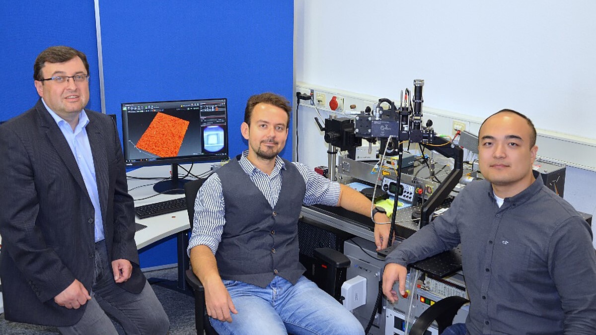 Drei Personen sitzen vor einem optischen Messsystem im Optik-Labor.